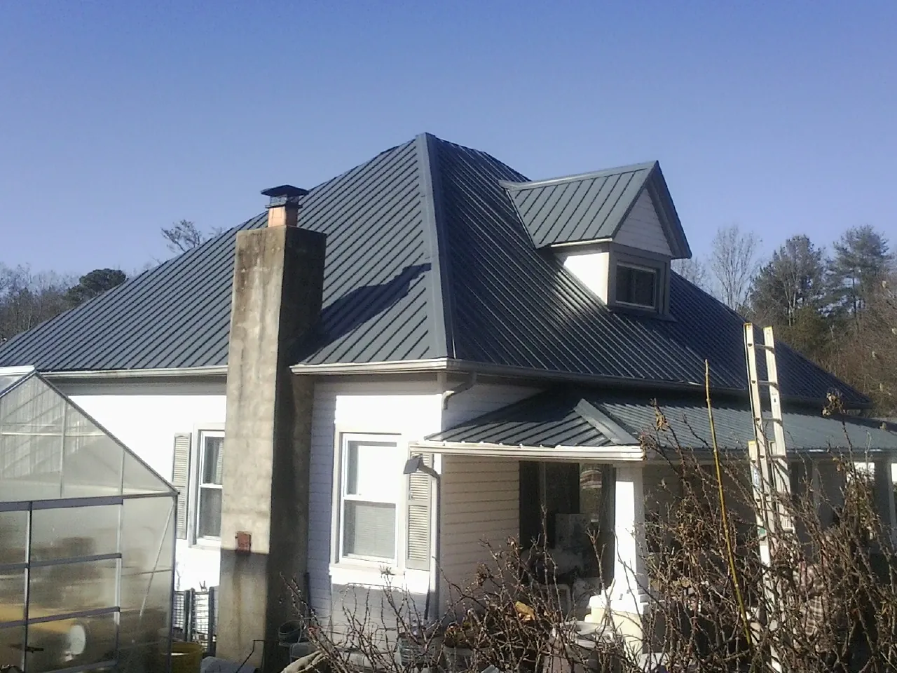 Dark blue standing seam metal roof on a white farmhouse with dormer — Slate & Tile Roof Repair by Roofing Brothers in Canal Winchester