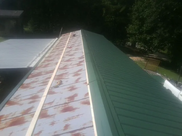 Old rusted panels beside newly installed green metal roofing — Wind Damage Roof Repair by Roofing Brothers in Canal Winchester