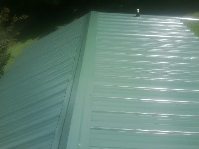 New green metal panels meeting at the ridge of a roof — Flat Roof Repair work by our crew in Canal Winchester