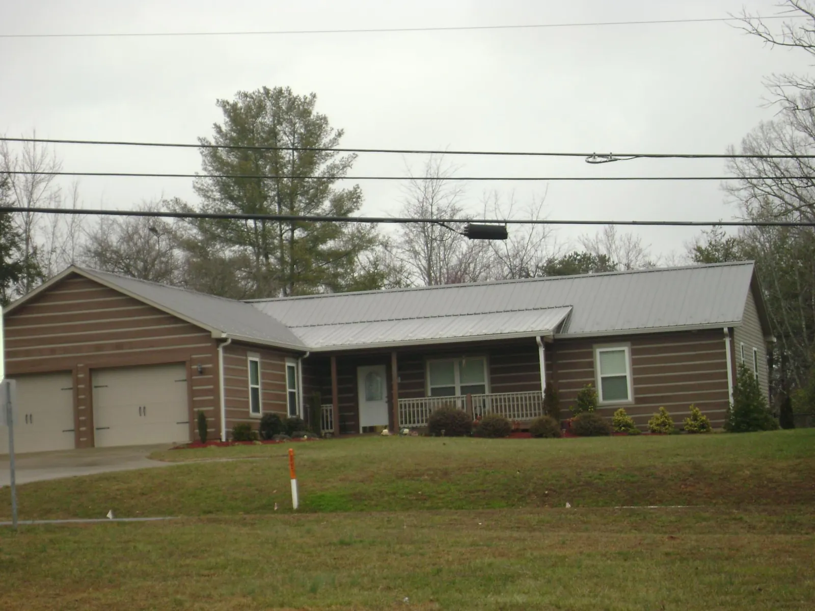 Gray metal roof on a log sided ranch home with a front porch in Canal Winchester