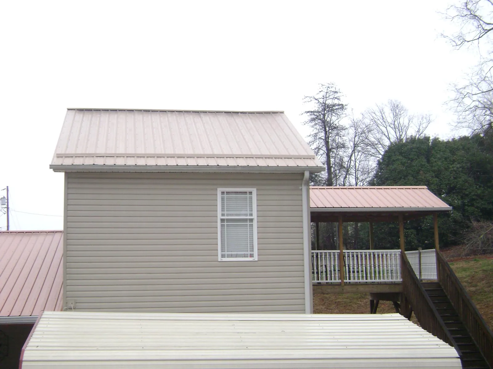 Tan metal roofs on a two story addition and attached porch, from a Roof Replacement job in Canal Winchester
