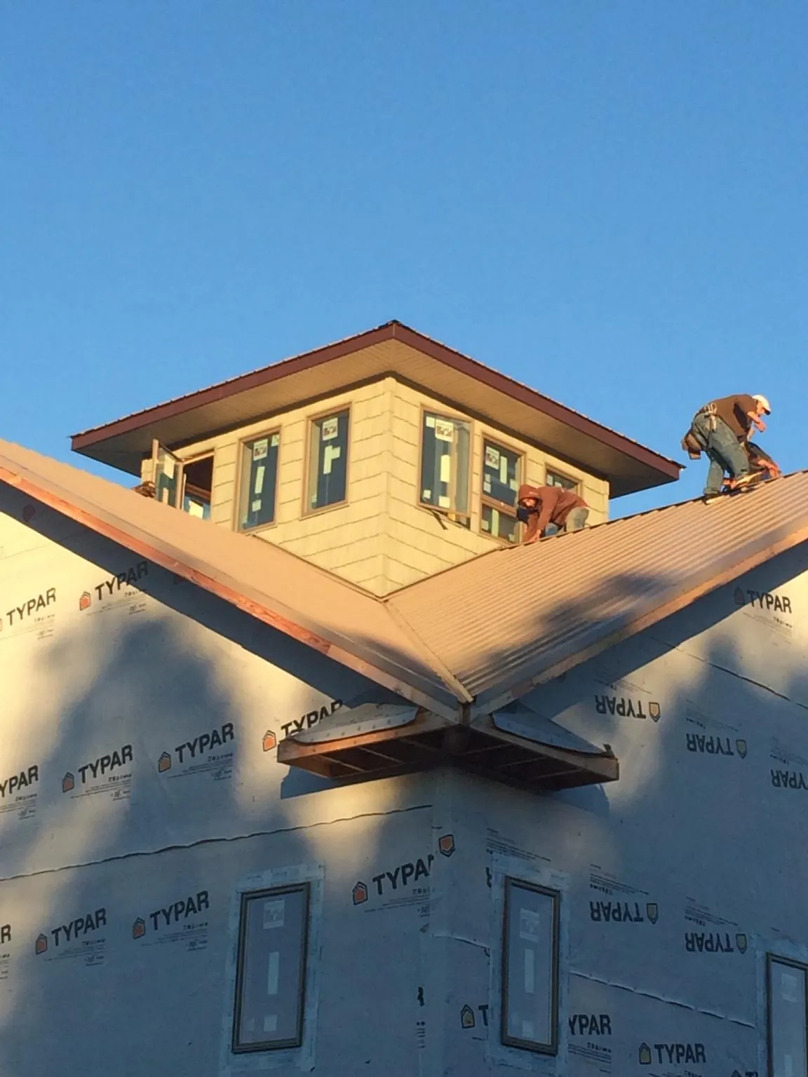 Roofers working around a rooftop cupola on a new metal roof at sunset — Roof Waterproofing in Canal Winchester by Roofing Brothers